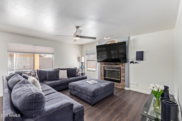 living room featuring ceiling fan, a fireplace, dark hardwood / wood-style floors, and a textured ceiling