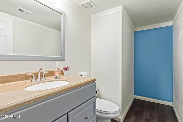 bathroom featuring hardwood / wood-style flooring, crown molding, vanity, and toilet