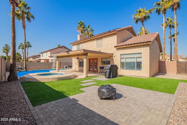 back of property featuring ceiling fan, a yard, a patio, an outdoor fire pit, and a pool with hot tub