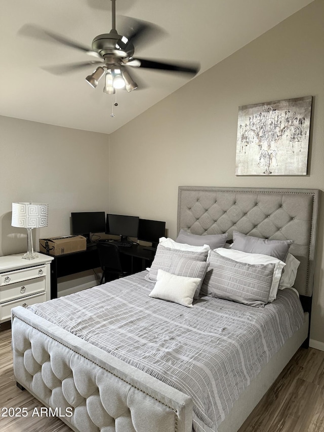 bedroom with ceiling fan, vaulted ceiling, and wood finished floors