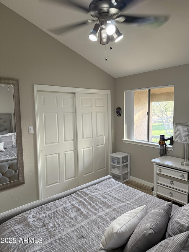 bedroom featuring a closet, baseboards, vaulted ceiling, ceiling fan, and wood finished floors
