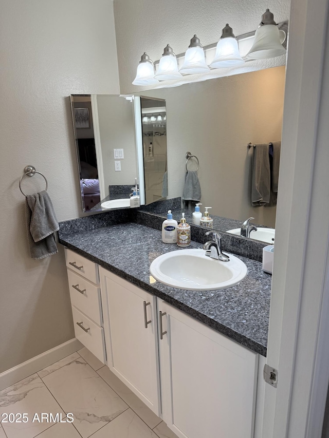 ensuite bathroom with ensuite bathroom, baseboards, marble finish floor, and vanity