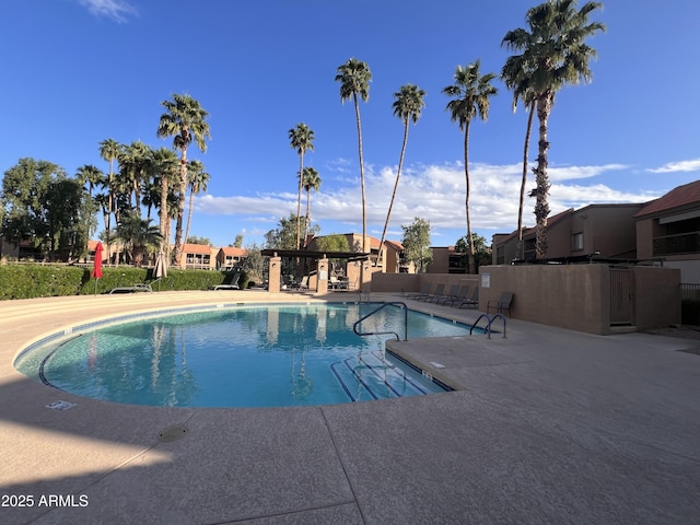 community pool with a patio and fence