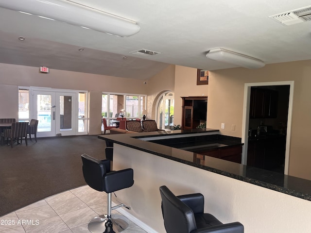 kitchen with open floor plan, visible vents, a kitchen breakfast bar, and dark countertops