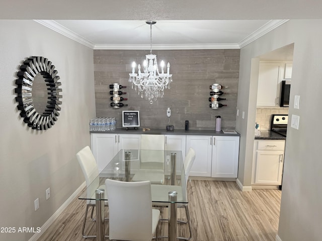 dining space featuring crown molding, baseboards, light wood-type flooring, and a chandelier