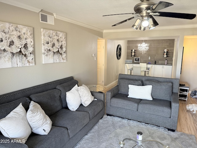 living area featuring wood finished floors, ceiling fan with notable chandelier, ornamental molding, and visible vents