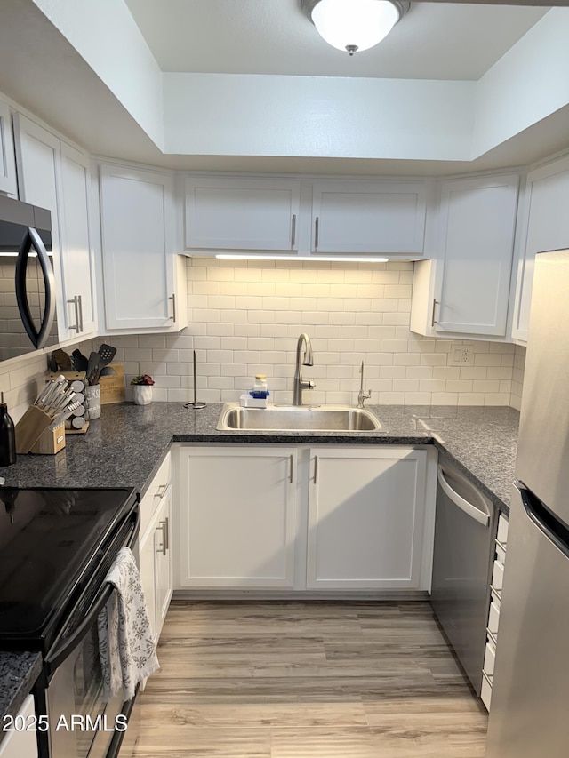 kitchen featuring appliances with stainless steel finishes, decorative backsplash, a sink, and white cabinetry