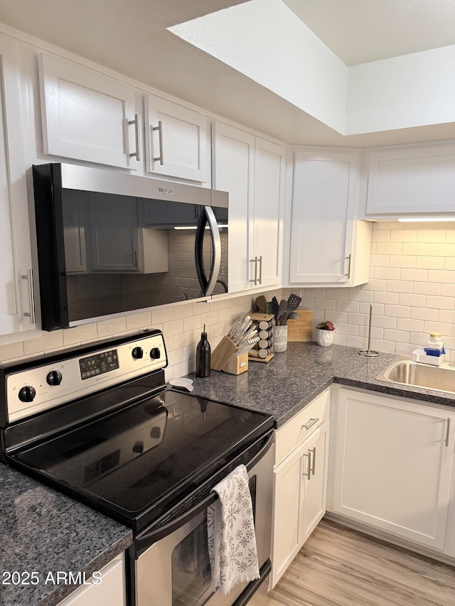 kitchen featuring stainless steel appliances, tasteful backsplash, white cabinetry, and a sink