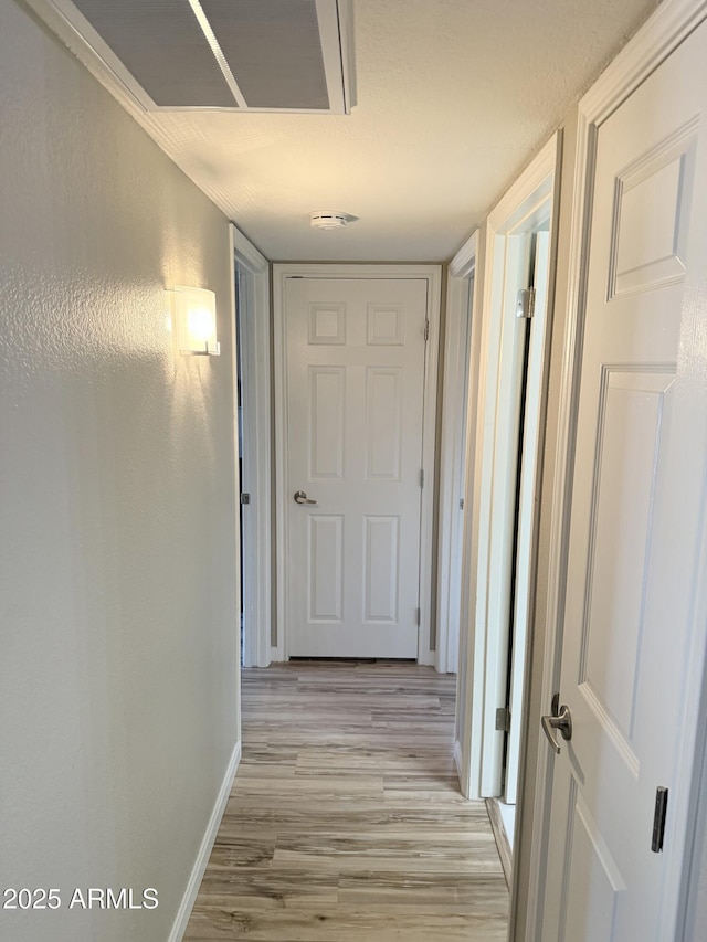 hallway with baseboards and light wood-style floors