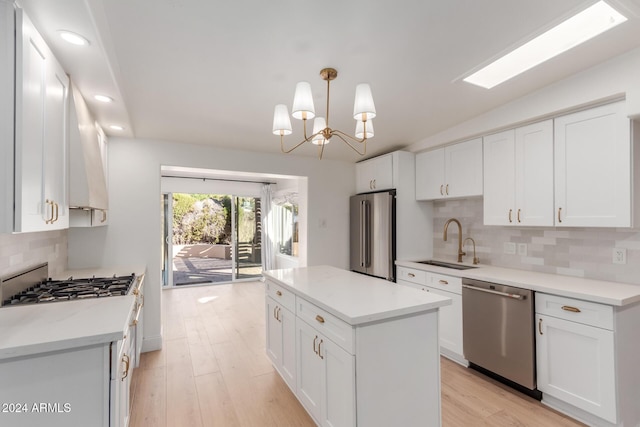 kitchen with white cabinets, sink, appliances with stainless steel finishes, and light hardwood / wood-style flooring