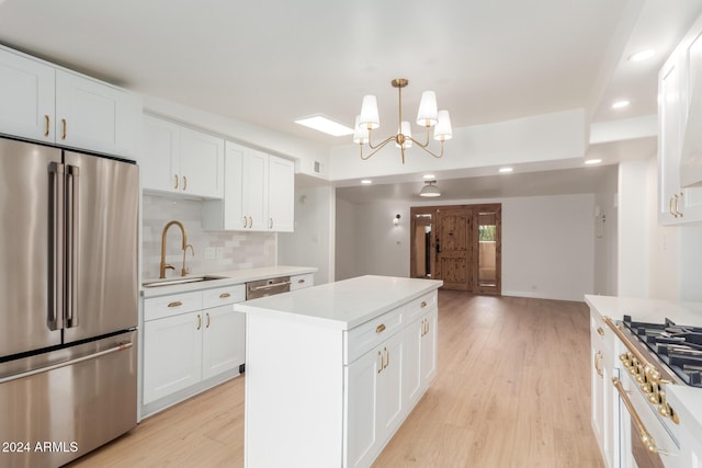 kitchen with pendant lighting, white cabinetry, appliances with stainless steel finishes, and light hardwood / wood-style flooring