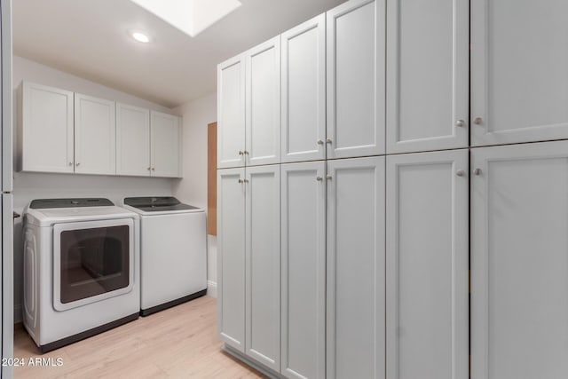 laundry room with cabinets, light wood-type flooring, and washing machine and clothes dryer