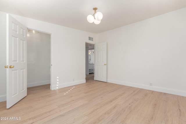 unfurnished bedroom featuring a closet, light hardwood / wood-style floors, and an inviting chandelier