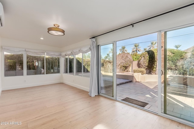 unfurnished sunroom featuring a healthy amount of sunlight and a wall mounted AC