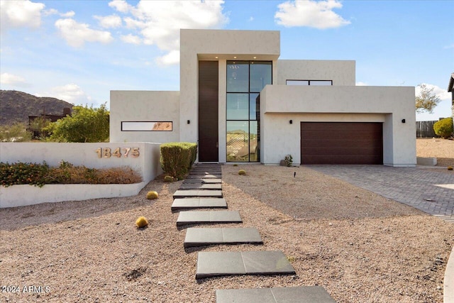 contemporary house with decorative driveway, an attached garage, and stucco siding