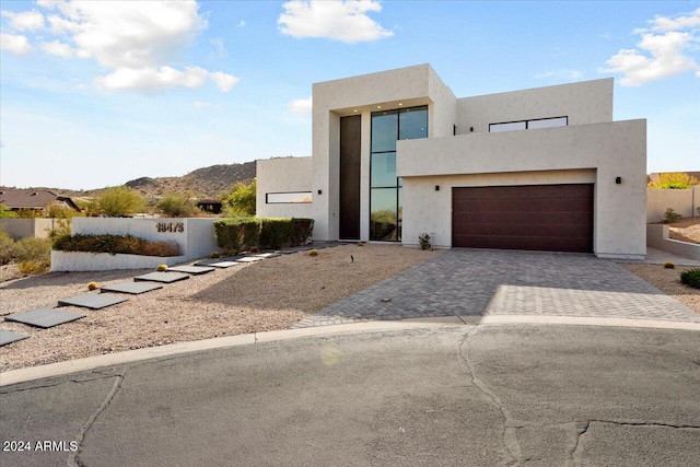 contemporary house featuring stucco siding, decorative driveway, and fence