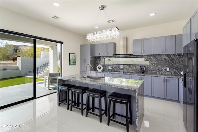 kitchen with backsplash, sink, dark stone counters, and wall chimney range hood