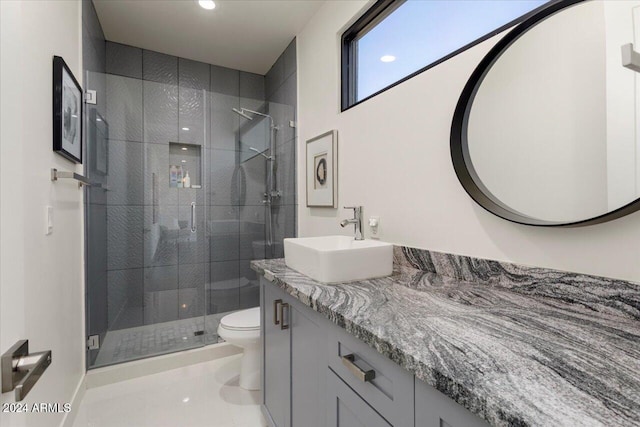 bathroom featuring tile patterned flooring, vanity, toilet, and walk in shower