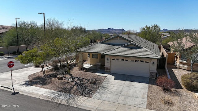 view of front facade with concrete driveway, a tile roof, stucco siding, a garage, and stone siding