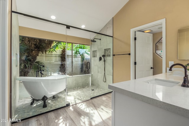 bathroom with hardwood / wood-style flooring, vanity, and plus walk in shower