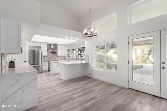 10338 E San Salvador Dr, Scottsdale, AZ 85258 - kitchen with stainless steel appliances, wall chimney range hood, a peninsula, light wood-style floors, and high vaulted ceiling