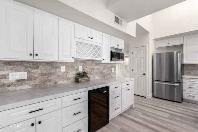 10338 E San Salvador Dr, Scottsdale, AZ 85258 - kitchen featuring stainless steel appliances, beverage cooler, light stone counters, and white cabinetry