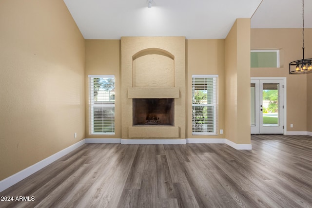 unfurnished living room with a large fireplace, wood-type flooring, and a high ceiling