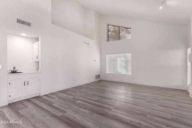 10338 E San Salvador Dr, Scottsdale, AZ 85258 - unfurnished living room featuring a towering ceiling, a sink, wood finished floors, and baseboards