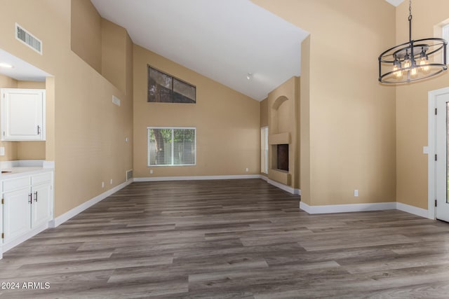 unfurnished living room with a chandelier, a large fireplace, high vaulted ceiling, and light hardwood / wood-style floors