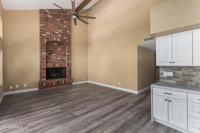 unfurnished living room featuring a fireplace, ceiling fan, dark wood-type flooring, and high vaulted ceiling