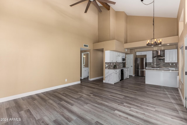 kitchen with white cabinetry, stainless steel appliances, wall chimney range hood, pendant lighting, and light hardwood / wood-style floors