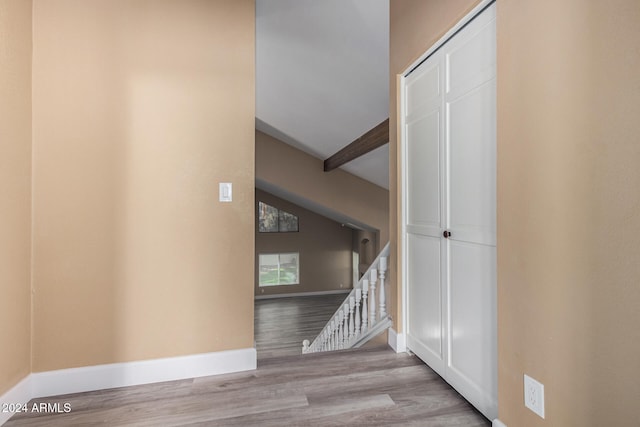 stairs with hardwood / wood-style floors and beam ceiling