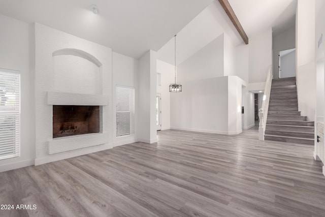 10338 E San Salvador Dr, Scottsdale, AZ 85258 - unfurnished living room with high vaulted ceiling, a fireplace, wood finished floors, stairway, and beamed ceiling