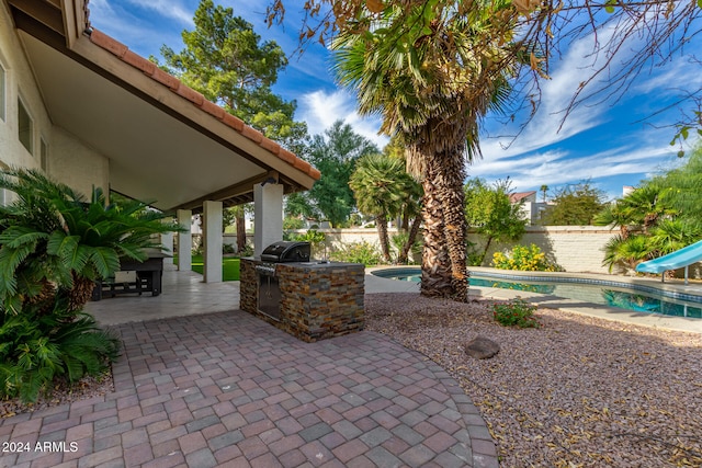 view of patio featuring area for grilling, a swimming pool with hot tub, and exterior kitchen