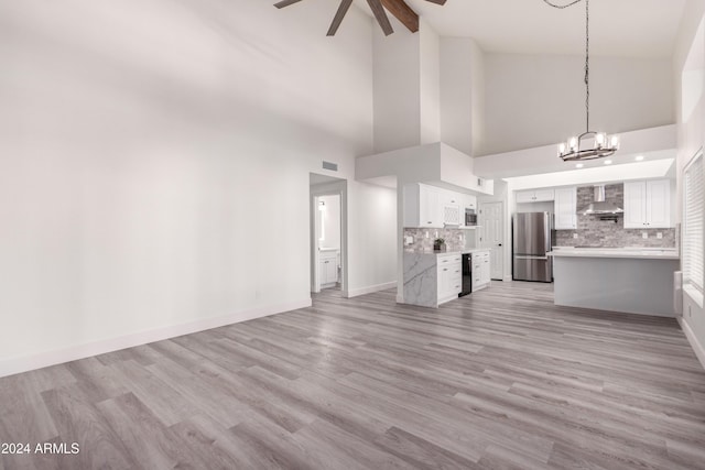 10338 E San Salvador Dr, Scottsdale, AZ 85258 - unfurnished living room with ceiling fan, high vaulted ceiling, a chandelier, light wood-type flooring, and baseboards