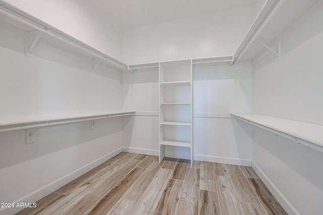 walk in closet with light hardwood / wood-style floors