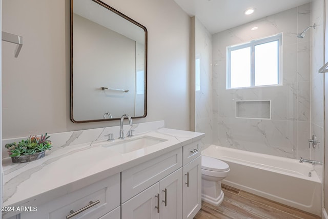 full bathroom with tiled shower / bath, vanity, wood-type flooring, and toilet