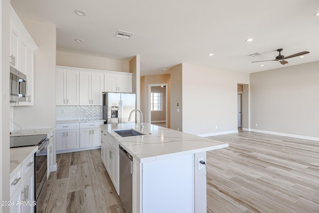 kitchen with white cabinets, appliances with stainless steel finishes, and a center island with sink