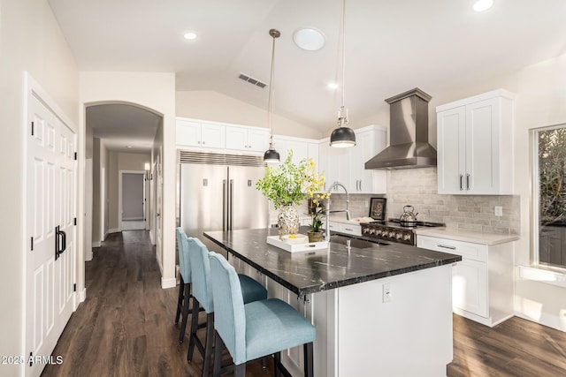 kitchen featuring a kitchen island, white cabinets, hanging light fixtures, and wall chimney exhaust hood