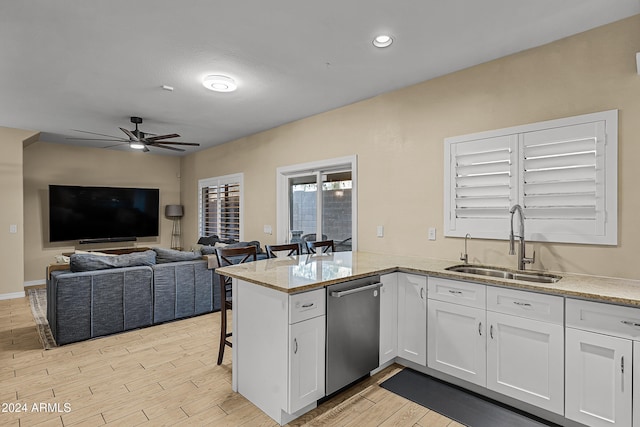 kitchen featuring light stone countertops, sink, kitchen peninsula, light hardwood / wood-style floors, and white cabinets