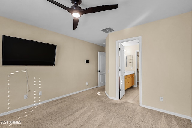 unfurnished bedroom with ceiling fan, light colored carpet, and ensuite bath