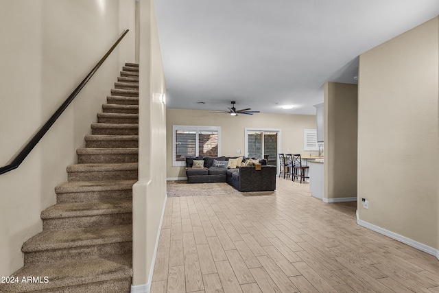 stairs featuring ceiling fan and hardwood / wood-style floors