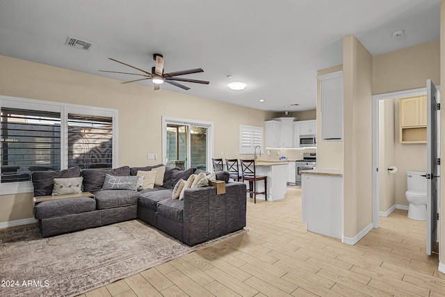 living room with ceiling fan and light hardwood / wood-style flooring