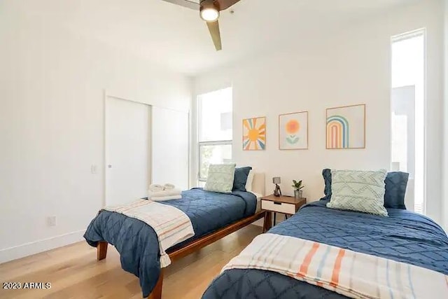 bedroom with a ceiling fan, a closet, baseboards, and light wood finished floors