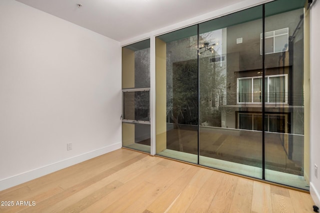 bathroom featuring baseboards, wood finished floors, and floor to ceiling windows