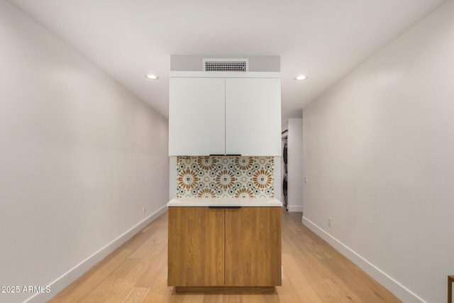 kitchen featuring light wood-style flooring, visible vents, baseboards, white cabinetry, and backsplash