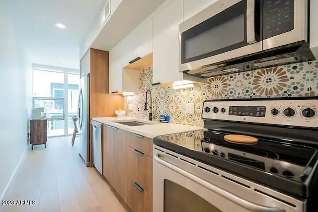 kitchen featuring tasteful backsplash, modern cabinets, stainless steel appliances, light countertops, and a sink