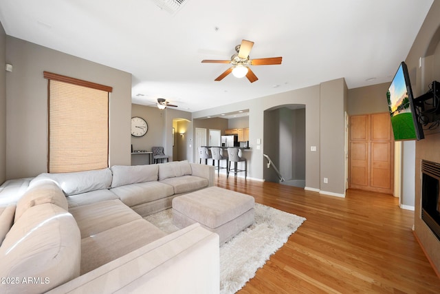 16600 N Thompson Peak Pkwy Unit 2006, Scottsdale, AZ 85260 - living room with arched walkways, ceiling fan, light wood-style flooring, a fireplace, and baseboards