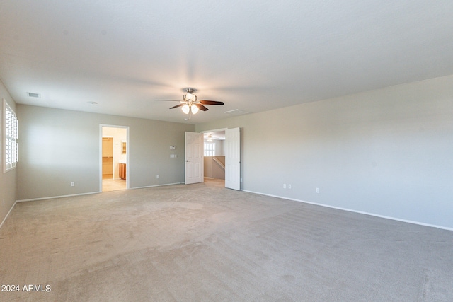 unfurnished bedroom featuring ensuite bath, ceiling fan, and light colored carpet