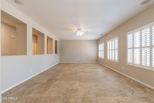 empty room with plenty of natural light, ceiling fan, and light tile floors